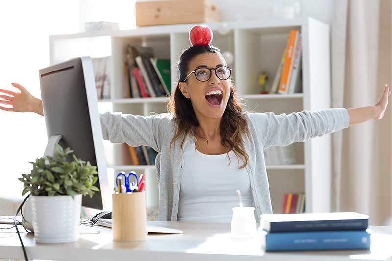 Mitarbeiterin balanciert einen Apfel auf dem Kopf